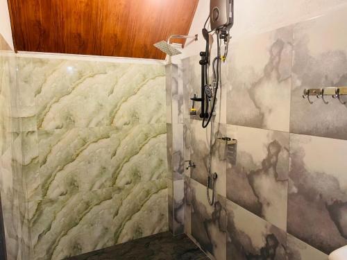 a shower stall in a bathroom with a marble wall at Rainforest River Cabana & Villa in Deniyaya