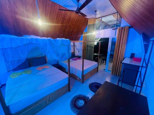 a room with a bed and a desk and a table at Rainforest River Cabana & Villa in Deniyaya