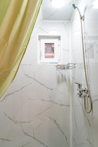 a white bathroom with marble floors and a shower at A-frame Sky in Karakol