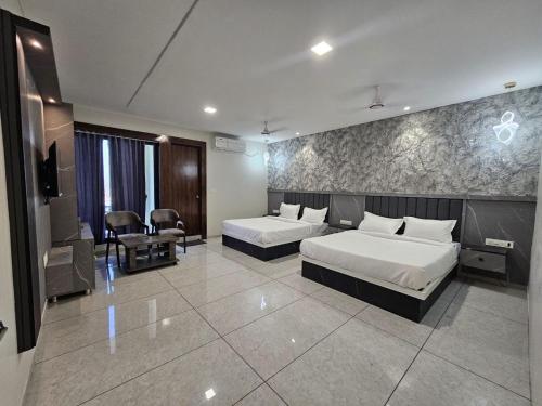 a hotel room with two beds and a television at Hotel Shiv Inn in Himatnagar