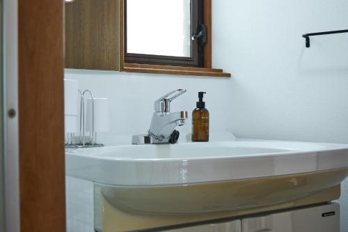 a bathroom sink with a bottle of soap on it at PinKumano by WhyKumano in Nachikatsuura