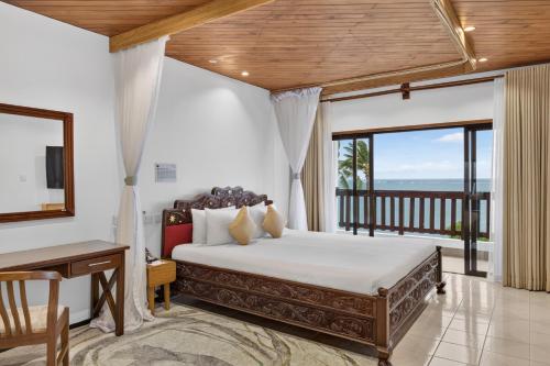 a bedroom with a large bed and a balcony at PrideInn Paradise Beach Resort & Spa Mombasa in Mombasa
