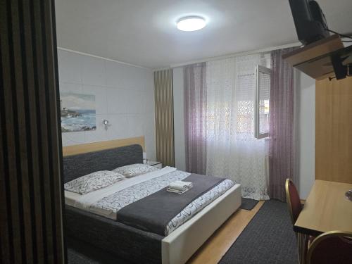 a bedroom with a bed and a table and a window at Vila Marija Rooms in Zagreb