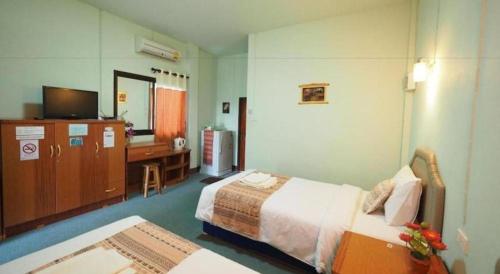 a room with two beds and a desk and a television at Phu Resort in Ban Choko