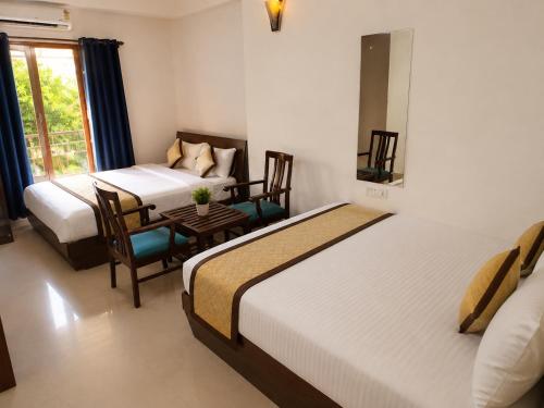 two beds in a room with a table and chairs at Beach Resort in 1 in North goa