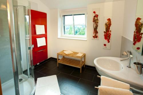 a bathroom with a tub and a sink and a red door at Boutique Hotel Toso Genussreich in Leutschach