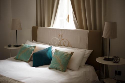 a white bed with four pillows on it with a window at Le Rondini in Grions del Torre