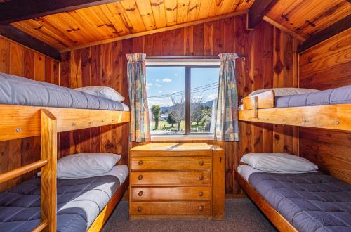 a bedroom with two bunk beds and a window at Ossies Motels and Chalets in Ohakune