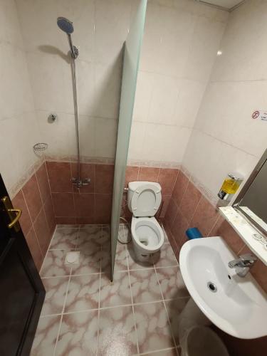 a bathroom with a shower and a toilet and a sink at Qimmat AlAwali Hotel in Az Zahrāʼ