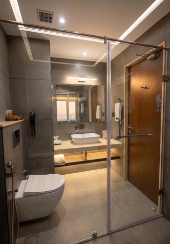 a bathroom with a shower and a toilet and a sink at Surya Grand Hotel in Kalpetta