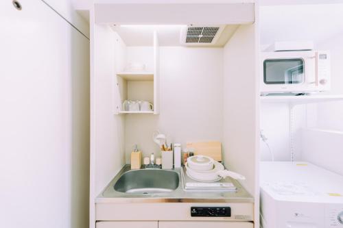 a kitchen with a sink and a microwave at Chic 1 Bedroom Space Near Nakasu in Fukuoka