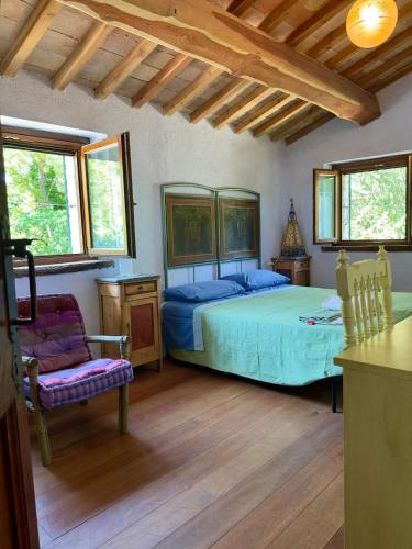 a bedroom with a bed and a chair and windows at B&B Mulini Venturi in Saludecio