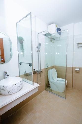 a bathroom with a glass shower and a toilet at Cortis Homestay in Nà Rẻ