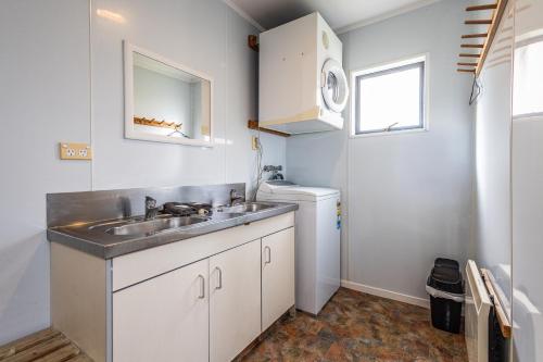 a small kitchen with a sink and a washing machine at Ossies Motels and Chalets in Ohakune