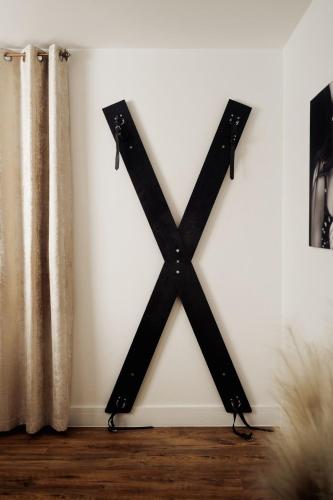 a black x on a wall with a curtain at Casa Amor - Kinky Hotel UK in Southampton