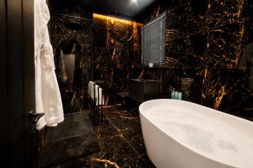 a bathroom with a white tub and a black marble wall at Casa Amor - Adult Only Retreat Midlands in Stoke on Trent