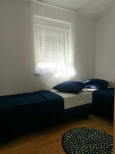 a bed with blue pillows in a room with a window at Apartman Lana in Klimno