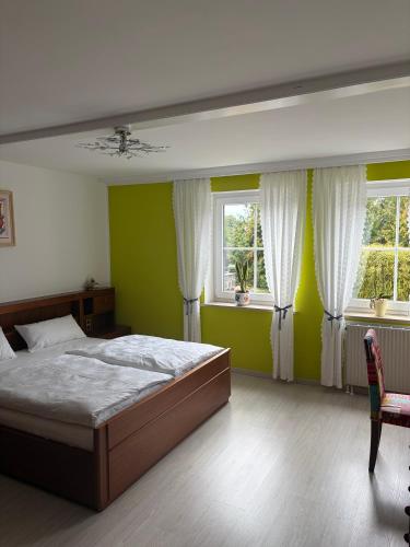 a bedroom with a large bed and two windows at Ferienwohnung Fuchs in Roding