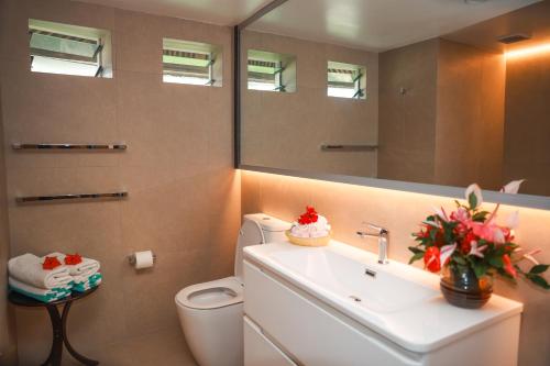 a bathroom with a sink and a toilet and a mirror at Le Lagoto Resort & Spa in Fagamalo