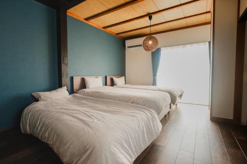 two beds in a room with blue walls and a window at Numazu Royal Retreat 201 in Numazu