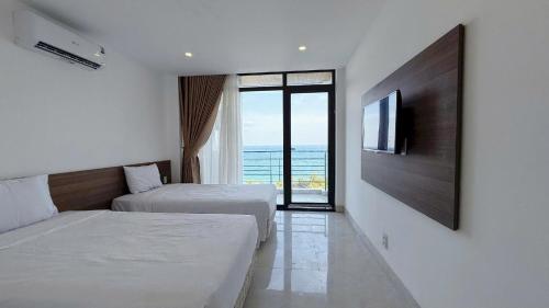 a bedroom with two beds and a flat screen tv at Aqua Hotel & Spa Managed by PD in Nha Trang