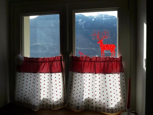 two windows with red and white curtains with a deer on them at B&B Ca' La Vedescia in Teglio