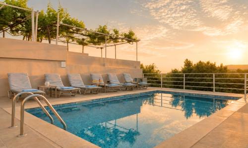 a pool with chaise lounge chairs next to a fence at Cretan Breeze Villa Heated Pool in Dhrámia