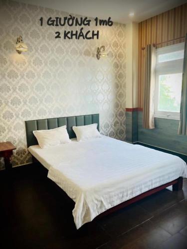 a bed in a bedroom with a sign on the wall at RUBY HOTEL in Cà Mau