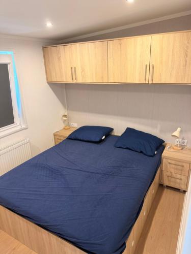 a bedroom with a bed with blue sheets and wooden cabinets at Chalet Pallegarste 153 in Mariënberg