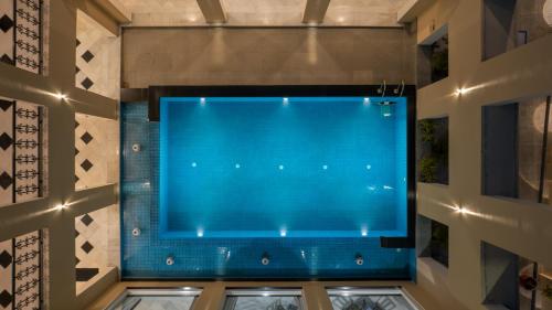 a large blue pool in a building with windows at Chez Lavania - A Boutique Stay in Udaipur