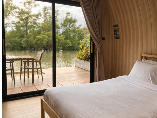 a bedroom with a bed and a deck with a table at rimbaymangroveresort in Ban Khlong Tamru
