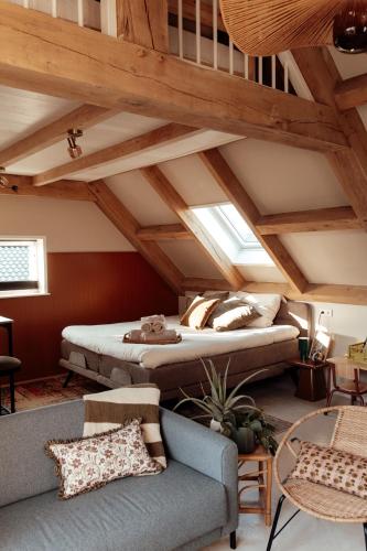 a attic room with a bed and a couch at Granny's B&B in Kapelle