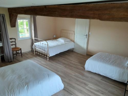 a bedroom with two beds and a chair at Domaine Cosme in Le Noyer-en-Ouche