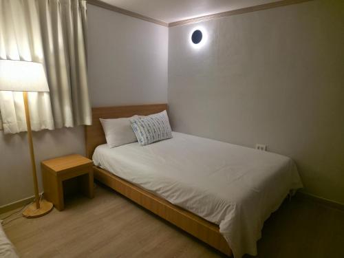 a small bedroom with a bed and a lamp at 고요스테이 in Chuncheon