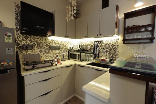 a small kitchen with white cabinets and a microwave at Shalom in Colva