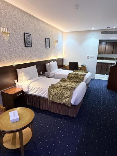 a hotel room with two beds and a table at Maysan Al Safa Hotel in Mecca
