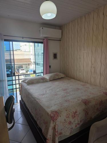 a bedroom with a bed and a large window at Pousada de Isa in Palhoça
