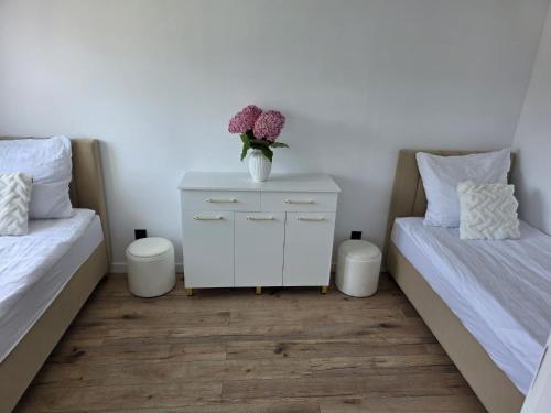 a bedroom with two beds and a vase of flowers on a night stand at Apartament "Agatka" in Hel