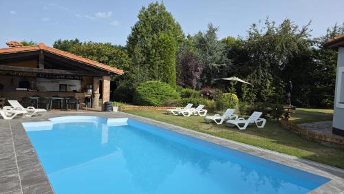 a swimming pool with chairs and a house at Hotel Jardín de Aura in Muros de Nalón