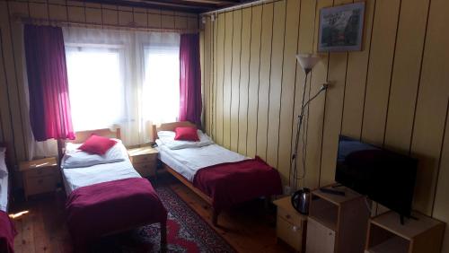 a room with two beds and a tv and a window at Nad Bałtykiem in Mrzeżyno