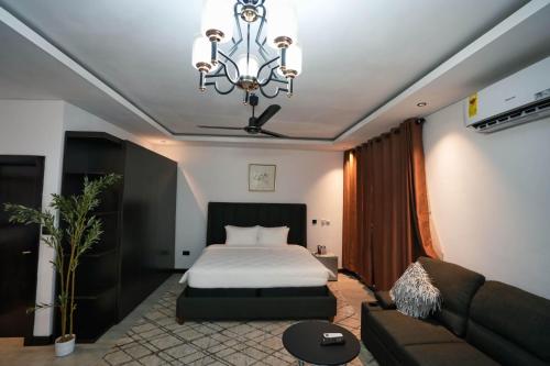 a bedroom with a bed and a couch and a chandelier at Newport Hotel in Atimpoko