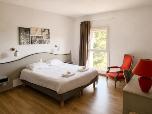 a bedroom with a bed and a red chair at Chambres de la Bastide des Joncas in Martigues
