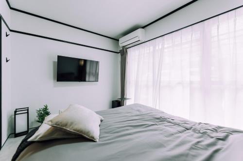 a bedroom with a bed and a tv on the wall at Work Ready Stay - Quiet Nakasu 202 in Fukuoka