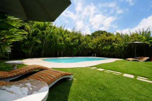 a swimming pool in a yard with an umbrella at Lukas Garden Accra Exclusive Resort in Accra