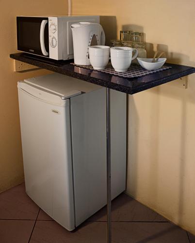 a counter with bowls and a microwave on top of a refrigerator at Lallapanzi Country Stay in Ermelo