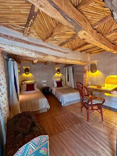 a bedroom with two beds and a chair in a room at Maison d'hôtes de charme Kasbah de Mimi Gorges du Dades in Aït Yous