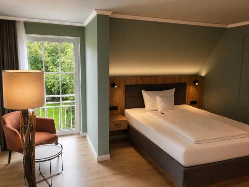 a bedroom with a bed and a chair and a window at Hotel Inselfriede in Spiekeroog