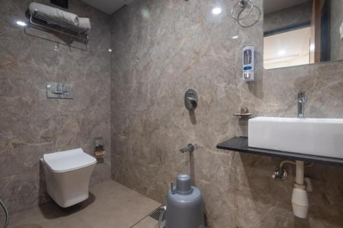 a bathroom with a white sink and a toilet at Hotel Avion Park Executive in Mumbai