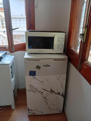 a microwave sitting on top of a refrigerator at Castel bungalow in Palafolls