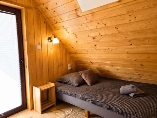a bed in a room with a wooden wall at Domek Pod Tylką in Grywałd